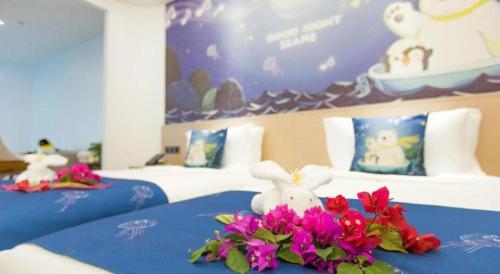 two beds with flowers and stuffed animals on them at Beluga Sanya Discovery Ocean World in Shangsimacun