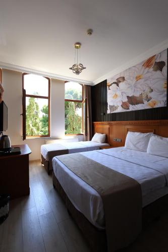 a hotel room with two beds and two windows at New House Hotel in Istanbul