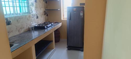 a kitchen with a stove and a refrigerator in it at Beverly Dinesh Homestay in Tiruvannāmalai
