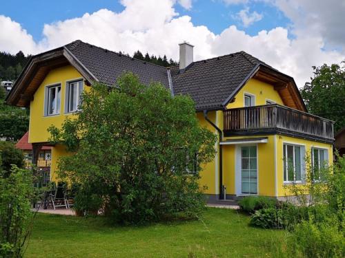 a yellow house with a black roof at Holiday home Anna Comfortable Vacation Home in Faak am See