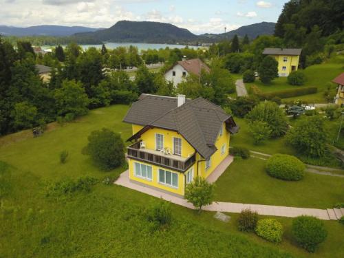a yellow house with a black roof on a green field at Holiday home Anna Comfortable Vacation Home in Faak am See