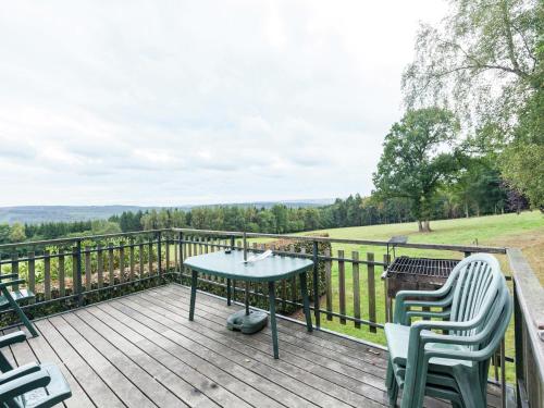 a wooden deck with a table and chairs on it at Cozy Cottage, Basse-Bodeux in Trois-Ponts
