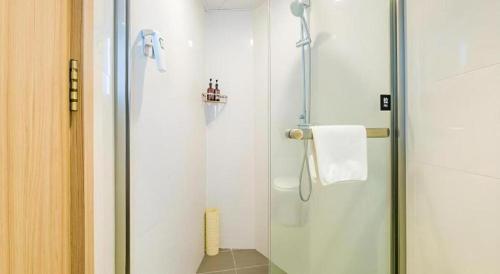 a shower with a glass door in a bathroom at GreenTree Inn Shanghai Jingan Railway Station Xinzha Road Business Hotel in Shanghai
