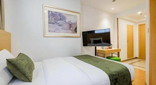 a hotel room with a bed and a flat screen tv at GreenTree Inn Shanghai Jingan Railway Station Xinzha Road Business Hotel in Shanghai