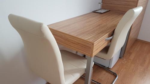 a wooden table with two white chairs around it at B&B By The Way in Ljubljana