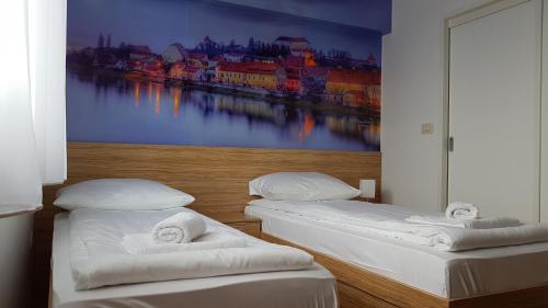 two beds in a room with a painting on the wall at B&B By The Way in Ljubljana