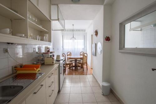 eine Küche mit weißen Schränken und ein Esszimmer in der Unterkunft Jelena Apartment in Split