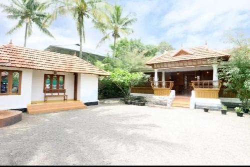 a house with a pavilion and palm trees at AVERA Heritage Homestay in Thekkady