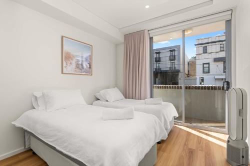 two beds in a room with a window at Al Mare Escape in Kiama
