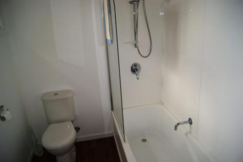 a white bathroom with a shower and a toilet at Inlet Side Eden in Inverloch