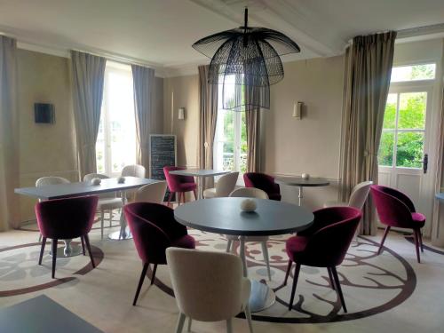 a dining room with tables and chairs and windows at Logis Hotels Restaurants- Villa des Bordes in Cléry-Saint-André