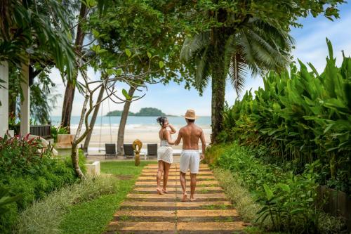 a man and a woman walking down a path by the beach at Barali Beach Resort Koh Chang in Ko Chang