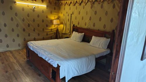 a bedroom with a bed with a wooden headboard at Quila Camps and Resort, Burja in Alwar
