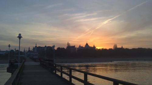 a sunset over the water with a pier and buildings at Ferienwohnung Regina in Zinnowitz