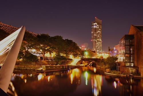 a city skyline at night with a river and buildings at The Manchester Deansgate Hotel, by IHG in Manchester