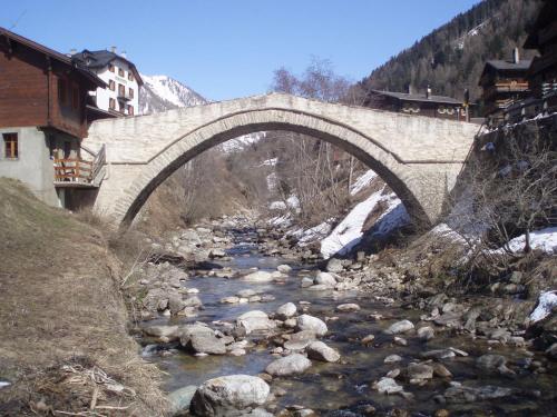 a stone bridge over a river in a town at Chalet in Wiler near Ski Lift & Views in Fiesch