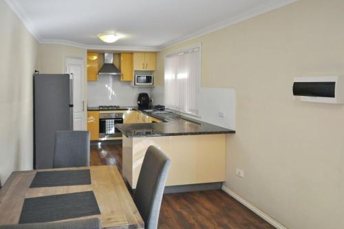 a kitchen with a wooden table and a dining room at Pilbara Cabin Affordable 1x1 in Port Hedland