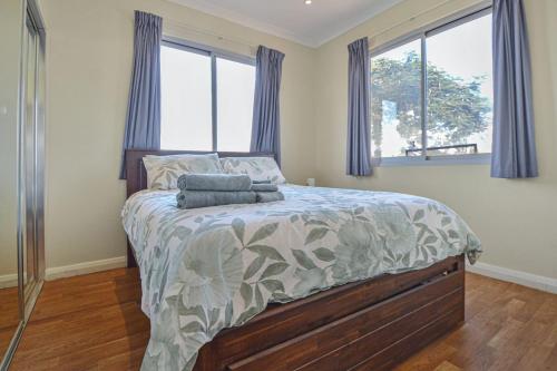 a bedroom with a large bed with blue curtains at Marvellous McKay 3x2 Close to CBD in Port Hedland