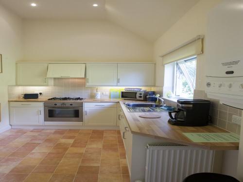 a kitchen with white cabinets and a wooden counter top at Cottage in Jedburgh with Stunning Views in Jedburgh