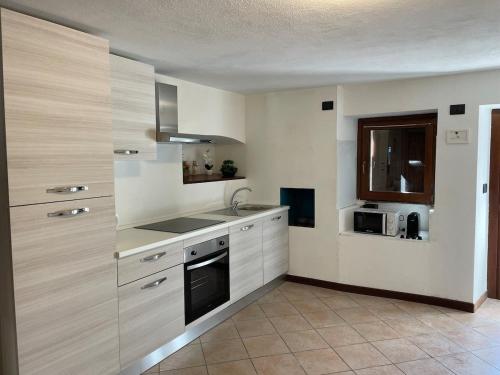a kitchen with white cabinets and a sink and a microwave at Valmaison - your cottage in the historic center in Aosta