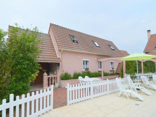 a house with a white fence and chairs and an umbrella at Holiday Home Folleville near Asterix Park in Sourdon