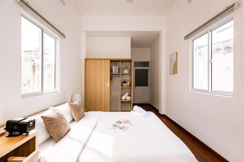 a white bedroom with a large bed and windows at The Hammond Saigon 3 in Ho Chi Minh City