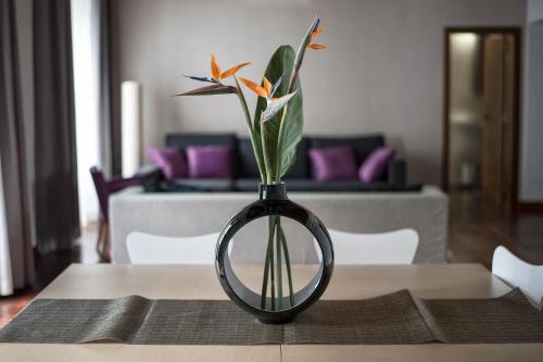 a black vase with flowers in it on a table at Anchieta 60 in La Laguna