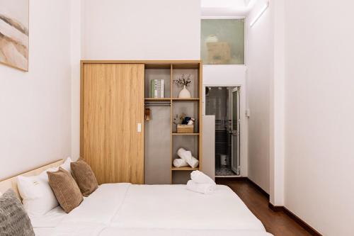 a bedroom with a white bed and a wooden cabinet at The Hammond Saigon 3 in Ho Chi Minh City