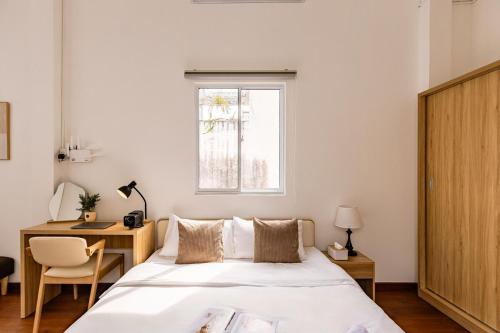 a bedroom with a bed and a desk and a window at The Hammond Saigon 3 in Ho Chi Minh City