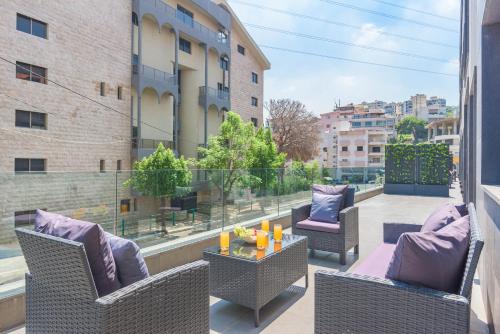 a balcony with wicker chairs and a table with candles at Grey - Elegant Apartments in Awkar in Dbayeh