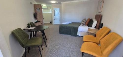 a room with a bed and a table and chairs at The Molong Motor Inn in Molong