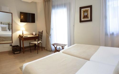 a hotel room with two white beds and a desk at Le Petit Boutique Hotel in Santander