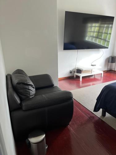 a living room with a black couch and a flat screen tv at Corazón de México in Mexico City