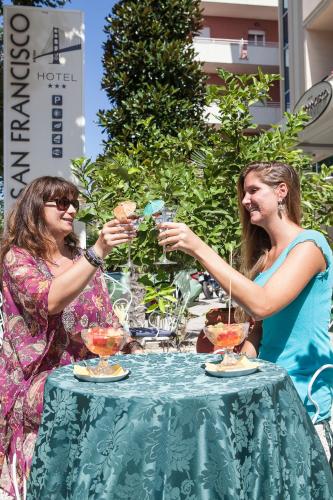 two women holding up wine glasses at a table at Hotel San Francisco Spiaggia in Rimini