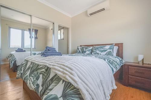 a bedroom with two beds and a large mirror at Terrific Townhouse 3x2 in CBD in Port Hedland