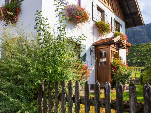 a house with flowers in front of a fence at Alpenapartment mit Garten in Trauchgau