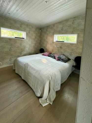 ein Schlafzimmer mit einem Bett in einem Zimmer mit zwei Fenstern in der Unterkunft Architect-Designed Villa With Pool Near Stockholm in Värmdö