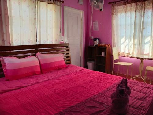 a pink bedroom with a large bed with pink sheets at Ban Rai Rabeang Mok in Khao Kho