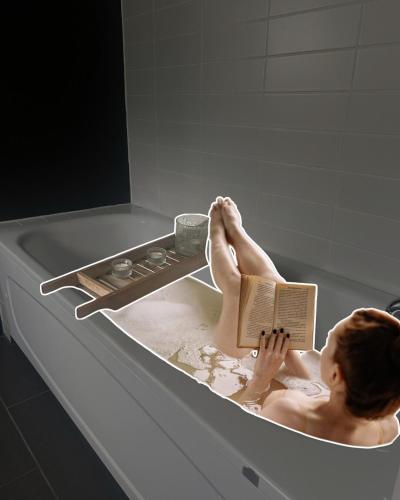 a woman sitting in a bath tub reading a book at Enjoy comfort and the view 2,5 km away from Color Line in Larvik