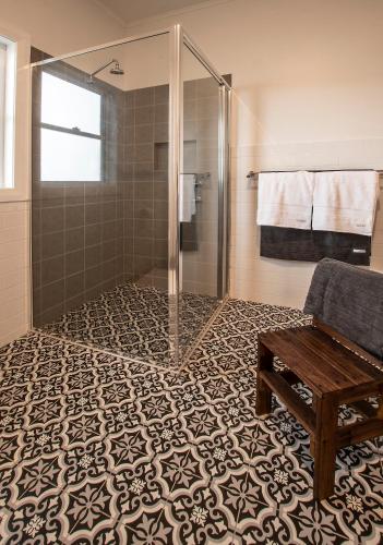 a bathroom with a shower and a bench on a tile floor at Cozy Cottage Blue Mountains in Lowther