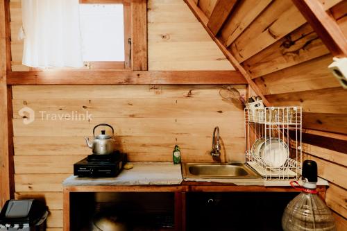 a kitchen counter with a sink and a window at Quenz Cabin By Travelink in Dieng