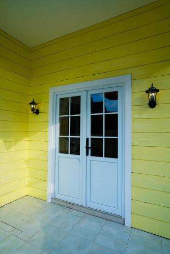 a white door on the side of a yellow house at Charming cozy House in Yogya, 15Min from Prambanan in Kalasan