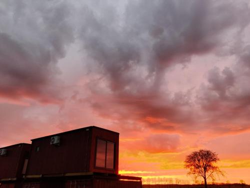 a cloudy sky with a building and a tree at Betuwe Lodge 1 in Tricht