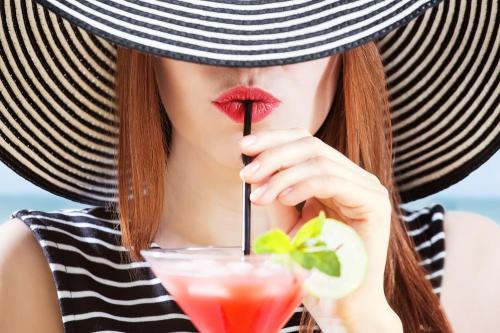 a woman wearing a straw hat and lipstick with a drink at The Broadway Hotel in Llandudno