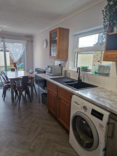 a kitchen with a washing machine and a dining room at 3-Bed Home, Garden, Free Parking,Greater London in Erith