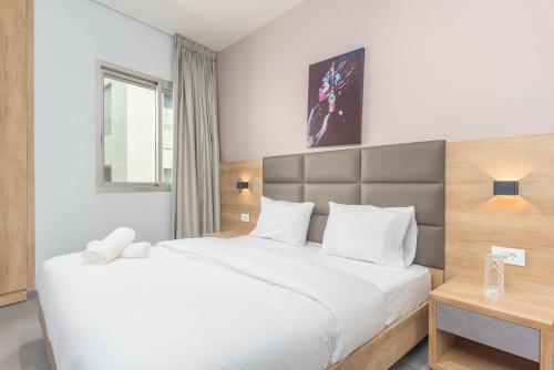 a bedroom with a large white bed and a table at Grey - Elegant Apartments in Awkar in Dbayeh