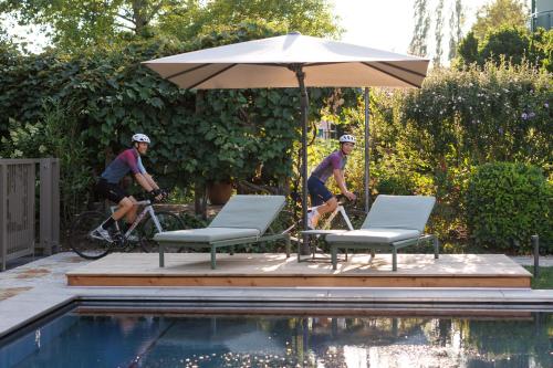 two men riding bikes next to a pool with an umbrella at Weinlandhof in Gamlitz