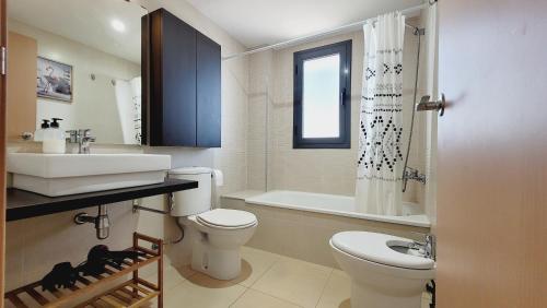a bathroom with a toilet and a sink and a tub at Panoramic Sunset Delta in Deltebre