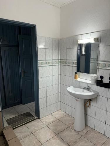 baño con lavabo, espejo y puerta en Makepe House, en Douala