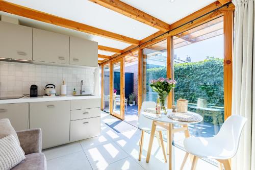 a kitchen with white cabinets and a table with flowers on it at Casa Duna Domburg in Domburg
